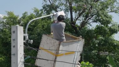 Yükseklik kaldırma platformunda çalışan işçiler yeni sokak lambaları kuruyor. Elektrik işçisi sokak lambasını monte ediyor. Eski lambaları yeni LED ışıklandırmalarla değiştiriyoruz. Teknisyen ışık tamir direği