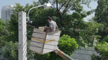 Yükseklik kaldırma platformunda çalışan işçiler yeni sokak lambaları kuruyor. Elektrik işçisi sokak lambasını monte ediyor. Eski lambaları yeni LED ışıklandırmalarla değiştiriyoruz. Teknisyen ışık tamir direği