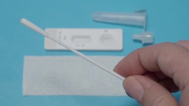 Hızlı antijen test kiti ya da ATK ve mavi arka plan kullanan insan elleri. 15 dakika içinde antikorları ve bağışıklığı tespit etmek için Covid 19 hızlı antikor test kiti. Kolay Koronavirüs Koruyucu Kontrolü.