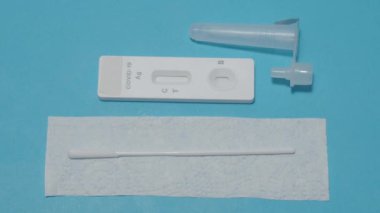 Hızlı antijen test kiti ya da ATK ve mavi arka plan kullanan insan elleri. 15 dakika içinde antikorları ve bağışıklığı tespit etmek için Covid 19 hızlı antikor test kiti. Kolay Koronavirüs Koruyucu Kontrolü.