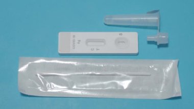 Hızlı antijen test kiti ya da ATK ve mavi arka plan kullanan insan elleri. 15 dakika içinde antikorları ve bağışıklığı tespit etmek için Covid 19 hızlı antikor test kiti. Kolay Koronavirüs Koruyucu Kontrolü.