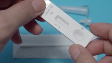 Hızlı antijen test kiti ya da ATK ve mavi arka plan kullanan insan elleri. 15 dakika içinde antikorları ve bağışıklığı tespit etmek için Covid 19 hızlı antikor test kiti. Kolay Koronavirüs Koruyucu Kontrolü.