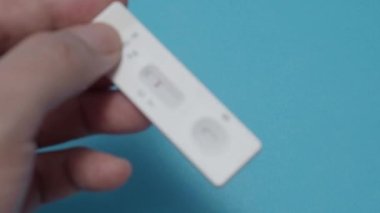 Hızlı antijen test kiti ya da ATK ve mavi arka plan kullanan insan elleri. 15 dakika içinde antikorları ve bağışıklığı tespit etmek için Covid 19 hızlı antikor test kiti. Kolay Koronavirüs Koruyucu Kontrolü.