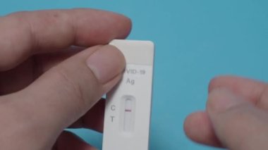 Hızlı antijen test kiti ya da ATK ve mavi arka plan kullanan insan elleri. 15 dakika içinde antikorları ve bağışıklığı tespit etmek için Covid 19 hızlı antikor test kiti. Kolay Koronavirüs Koruyucu Kontrolü.