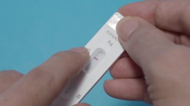 Hızlı antijen test kiti ya da ATK ve mavi arka plan kullanan insan elleri. 15 dakika içinde antikorları ve bağışıklığı tespit etmek için Covid 19 hızlı antikor test kiti. Kolay Koronavirüs Koruyucu Kontrolü.