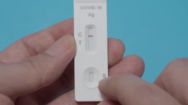 Hızlı antijen test kiti ya da ATK ve mavi arka plan kullanan insan elleri. 15 dakika içinde antikorları ve bağışıklığı tespit etmek için Covid 19 hızlı antikor test kiti. Kolay Koronavirüs Koruyucu Kontrolü.