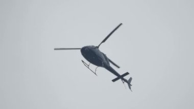Gökyüzünde uçan helikopter alçak açılı çekim görüntüsü. Helikopter havalandı. Dikey ve yatay hareket edebilme kabiliyeti, hareket yönü pervanenin pervanesi tarafından kontrol edilir..