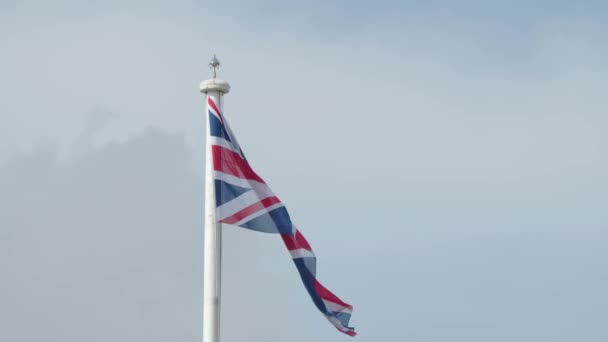 風になびく旗竿にイギリスの本物のユニオンジャックフラグ イギリスの国旗のビデオの風の中で手を振っイギリス イギリスEu離脱 イギリス植民地の国旗 イギリス国旗 — ストック動画