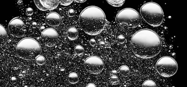 Soda su kabarcıkları siyah arka planda su altında sıçrıyor. Karbonat içeceği konseptini canlandırmak için suyun altında bir patlama gibi köpüren ve yüzeye doğru yüzen kola sıvısı dokusu..