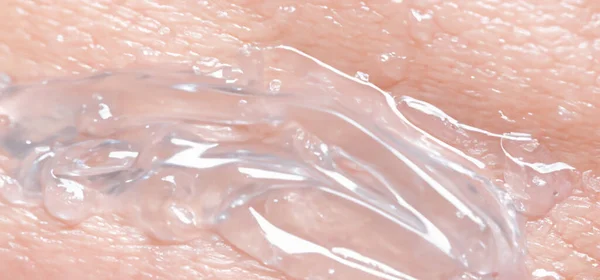 胶原蛋白和透明质血清凝胶在皮肤上 喷溅的透明质凝胶 皮肤上有液体透明质酸凝胶 人类皮肤背景上的复合水凝胶质感 纹理背景 护肤产品 — 图库照片