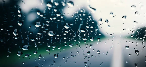 Regenschauer Auf Autoscheibe Oder Autoscheibe Und Verschwommene Straße Hintergrund Autofahren lizenzfreie Stockfotos