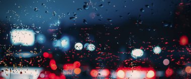 Yağmurlu havada araba sürüyorum. Yağmur mevsiminde araba ön camında ya da araba camında ve arka planda bulanık trafik yolunda yağmur. Araba aynasına yağmur damlaları düşer. Yağmurda yol. Çiseleme yağmuru araba sürmeyi azaltır.