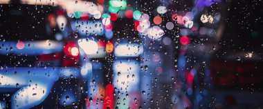 Yağmurlu havada araba sürüyorum. Yağmur mevsiminde araba ön camında ya da araba camında ve arka planda bulanık trafik yolunda yağmur. Araba aynasına yağmur damlaları düşer. Yağmurda yol. Çiseleme yağmuru araba sürmeyi azaltır.