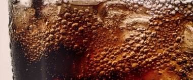 Kola ve buz dökülüyor. Kola soda ve buz fışkırıyor ya da yüzeye çıkıyor. Kola suyundaki buzu kapat. Bardakta kabarcıklar olan karbonat içeceği. Soğuk içecek arka planı