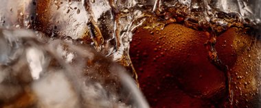 Kola ve buz dökülüyor. Kola soda ve buz fışkırıyor ya da yüzeye çıkıyor. Kola suyundaki buzu kapat. Bardakta kabarcıklar olan karbonat içeceği. Soğuk içecek arka planı