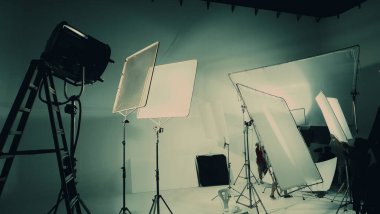 Film ekibi Lightman ve kameramanı büyük stüdyoda profosyonel ekipmanlarla birlikte çalışan video yapımcılarının silueti ya da B kaydı ya da TV reklam filmi çekimi.