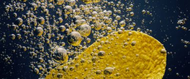 Altın yağlı suyun altında kızarmış patates cipsi. Kızarmış patates cipsi ve kızgın yağ kabarcıkları. Fast food ve aperatif. Su altında yağlı patates kızartması ya da yağlı arka planda patates cipsi.