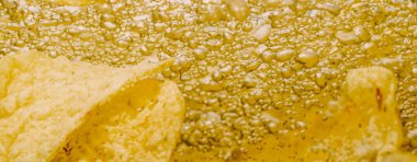 Altın yağlı suyun altında kızarmış patates cipsi. Kızarmış patates cipsi ve kızgın yağ kabarcıkları. Fast food ve aperatif. Su altında yağlı patates kızartması ya da yağlı arka planda patates cipsi.