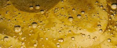 Altın yağlı suyun altında kızarmış patates cipsi. Kızarmış patates cipsi ve kızgın yağ kabarcıkları. Fast food ve aperatif. Su altında yağlı patates kızartması ya da yağlı arka planda patates cipsi.