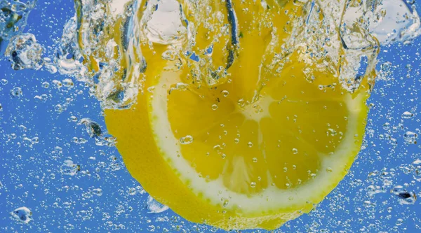ソーダの水または泡が付いているレモン スライス 爽やかなソーダトニックなカクテル グラスにレモンと氷のキューブを閉じました スプラッシュでライム スパークリングウォーター 冷たい飲み物 — ストック写真