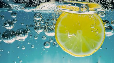 Taze sıkılmış limonata suları. Koyu mavi ya da siyah arka planda soda suyuna dökülen çiğ limonlar. Limonata ya da Highball limonlu kokteylleri kapatın. Soğuk, ferahlatıcı bir içecek.