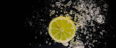 Taze sıkılmış limonata suları. Koyu mavi ya da siyah arka planda soda suyuna dökülen çiğ limonlar. Limonata ya da Highball limonlu kokteylleri kapatın. Soğuk, ferahlatıcı bir içecek.