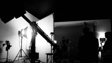 Film stüdyosunda profosyonel ışık ve kamera ekipmanları ve film yönetmeniyle profesyonel film ekibinin yer aldığı video prodüksiyon sahnelerinin silueti.