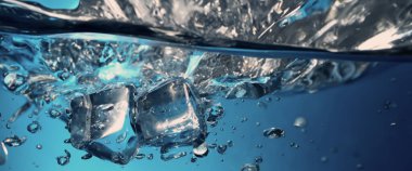 Su sıçratma ve buz küpü. Bir bardak suya buz sıçrıyor. Su altı buz küpleri berrak sulama arka planına dökülüyor. Serinletici bir içecek. Mavi arka planı olan bir bardaktaki buzlar