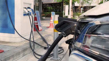 Elektrikli taşıt ya da EV araba park yeri şarj istasyonunda ve elektrik kablosu kablosu tıkanmış. Elektriği EV ya da hibrit araba aküsüne şarj edin. Dünya 'nın gelecekteki taşımacılığının yeşil enerjisi ve ekolojik gücü. EV gücü
