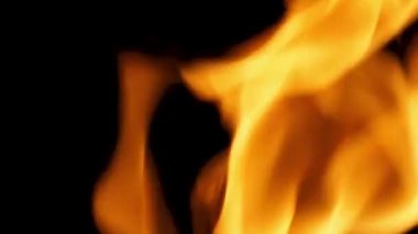Ateşin siyah arka planda yanma görüntülerini kapatın. Ateş sallıyor ve yanıyor. Bu da ısıyı temsil ediyor ve zarar veriyor. Kırmızı ateş ızgara ve yemek. El kamerası biçimi