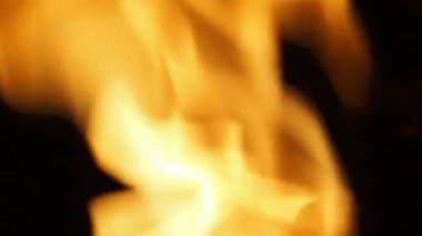 Ateşin siyah arka planda yanma görüntülerini kapatın. Ateş sallıyor ve yanıyor. Bu da ısıyı temsil ediyor ve zarar veriyor. Kırmızı ateş ızgara ve yemek. El kamerası biçimi