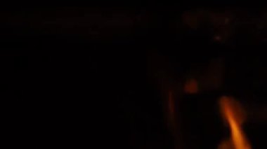 Ateşin siyah arka planda yanma görüntülerini kapatın. Ateş sallıyor ve yanıyor. Bu da ısıyı temsil ediyor ve zarar veriyor. Kırmızı ateş ızgara ve yemek. El kamerası biçimi