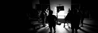 Tv reklam filmi çekimleri sahnesinin arkasındaki video görüntülerinin silueti. Film ekibi Lightman ve kameraman büyük stüdyoda yönetmen ve ekipman ile birlikte çalışıyorlar..