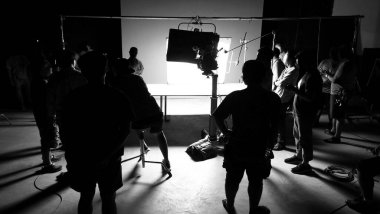 Tv reklam filmi çekimleri sahnesinin arkasındaki video görüntülerinin silueti. Film ekibi Lightman ve kameraman büyük stüdyoda yönetmen ve ekipman ile birlikte çalışıyorlar..