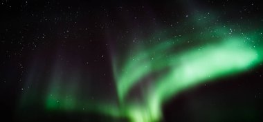 Aurora australis veya Aurora borealis veya yeşil kuzey ışıkları dağların üzerinde gökyüzü. Kutup ışıklarıyla gece gökyüzü. Güney ışıkları ve gerçek doğal kara arka plana karşı gece manzarası..