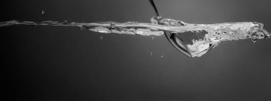 Bar kaşığıyla içki karıştırmak. Gümüş metal kaşık suları Votka Cin veya tekila gibi alkollü içecekleri karıştırır. Barmen kaşığı temiz suyun altında gri arka planda.