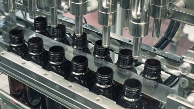 Modern fabrikada şişeler otomasyon makinesini dolduruyor. Endüstrideki şişeleri doldurma ve kapama teknolojisi gösterisi. Kusurlu ilaç şişelerinin incelenmesi. İlaç ve içecek imalatı.