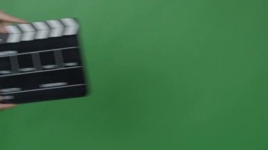 Yeşil ekran arka planında Eller tarafından alkışlanan el çırpma tahtası. Film yapımcısı yeşil kamera çerçevesinde film tahtasını vurdu. Alkış tahtası Chroma anahtar atışı. Yeşil ekran kompozit video üretimi.