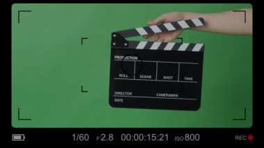 Yeşil ekran arka planında Eller tarafından alkışlanan el çırpma tahtası. Film yapımcısı yeşil kamera çerçevesinde film tahtasını vurdu. Alkış tahtası Chroma anahtar atışı. Yeşil ekran kompozit video üretimi.