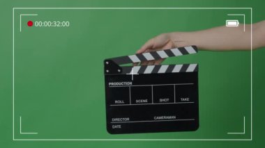 Yeşil ekran arka planında Eller tarafından alkışlanan el çırpma tahtası. Film yapımcısı yeşil kamera çerçevesinde film tahtasını vurdu. Alkış tahtası Chroma anahtar atışı. Yeşil ekran kompozit video üretimi.