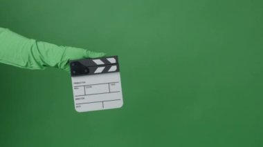 Yeşil ekran arka planında Eller tarafından alkışlanan el çırpma tahtası. Film yapımcısı yeşil kamera çerçevesinde film tahtasını vurdu. Alkış tahtası Chroma anahtar atışı. Yeşil ekran kompozit video üretimi.