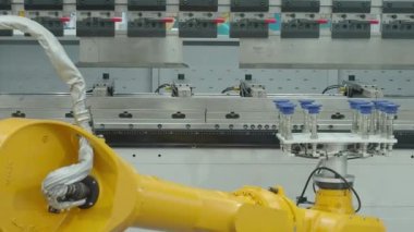 Vakumlu vakum bardaklı demo sarı robotik kol metal bükme işlevlerinde otomasyon gösteren bir fren makinesinin önünde çalışıyor. Gelişmiş otomatik üretim yüksek hassasiyet teknolojisi 