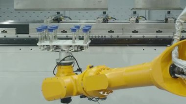 Vakumlu vakum bardaklı demo sarı robotik kol metal bükme işlevlerinde otomasyon gösteren bir fren makinesinin önünde çalışıyor. Gelişmiş otomatik üretim yüksek hassasiyet teknolojisi 