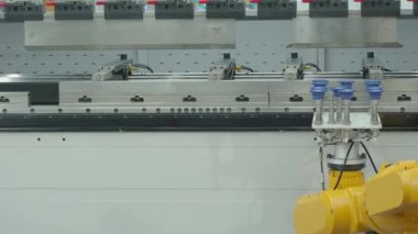 Vakumlu vakum bardaklı demo sarı robotik kol metal bükme işlevlerinde otomasyon gösteren bir fren makinesinin önünde çalışıyor. Gelişmiş otomatik üretim yüksek hassasiyet teknolojisi 