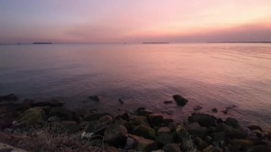 Sakin bir denizin üzerinde sakin bir günbatımı. Gökyüzünün altın rengi pembe ve mavi renkleri suya yansıyor. Sakin bir atmosfer huzur verici nefes kesici bir sahne yaratıyor. Rahatlamak için mükemmel..