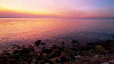 Sakin bir denizin üzerinde sakin bir günbatımı. Gökyüzünün altın rengi pembe ve mavi renkleri suya yansıyor. Sakin bir atmosfer huzur verici nefes kesici bir sahne yaratıyor. Rahatlamak için mükemmel..