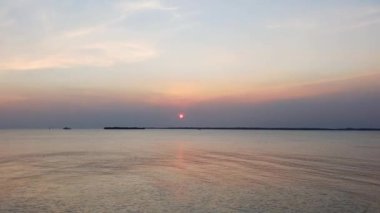 Sakin bir denizin üzerinde sakin bir günbatımı. Gökyüzünün altın rengi pembe ve mavi renkleri suya yansıyor. Sakin bir atmosfer huzur verici nefes kesici bir sahne yaratıyor. Rahatlamak için mükemmel..