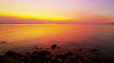 Sakin bir denizin üzerinde sakin bir günbatımı. Gökyüzünün altın rengi pembe ve mavi renkleri suya yansıyor. Sakin bir atmosfer huzur verici nefes kesici bir sahne yaratıyor. Rahatlamak için mükemmel..