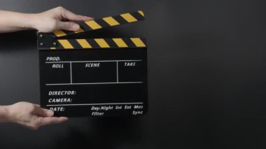 Klasik bir film sehpası ya da film tahtası tutuluyor ve karanlık bir arkaplana çarpılıyor. Eğlence sektöründe film yapımcılığı, film çekimi ve yaratıcı hikaye anlatımını sembolize eder..