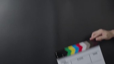 Klasik bir film sehpası ya da film tahtası tutuluyor ve karanlık bir arkaplana çarpılıyor. Eğlence sektöründe film yapımcılığı, film çekimi ve yaratıcı hikaye anlatımını sembolize eder..